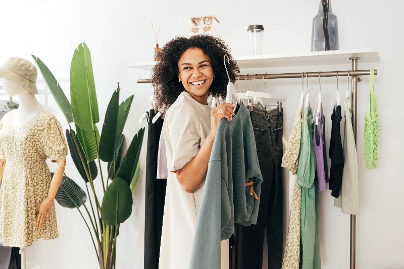 Laughing woman customer choosing sweater in a store